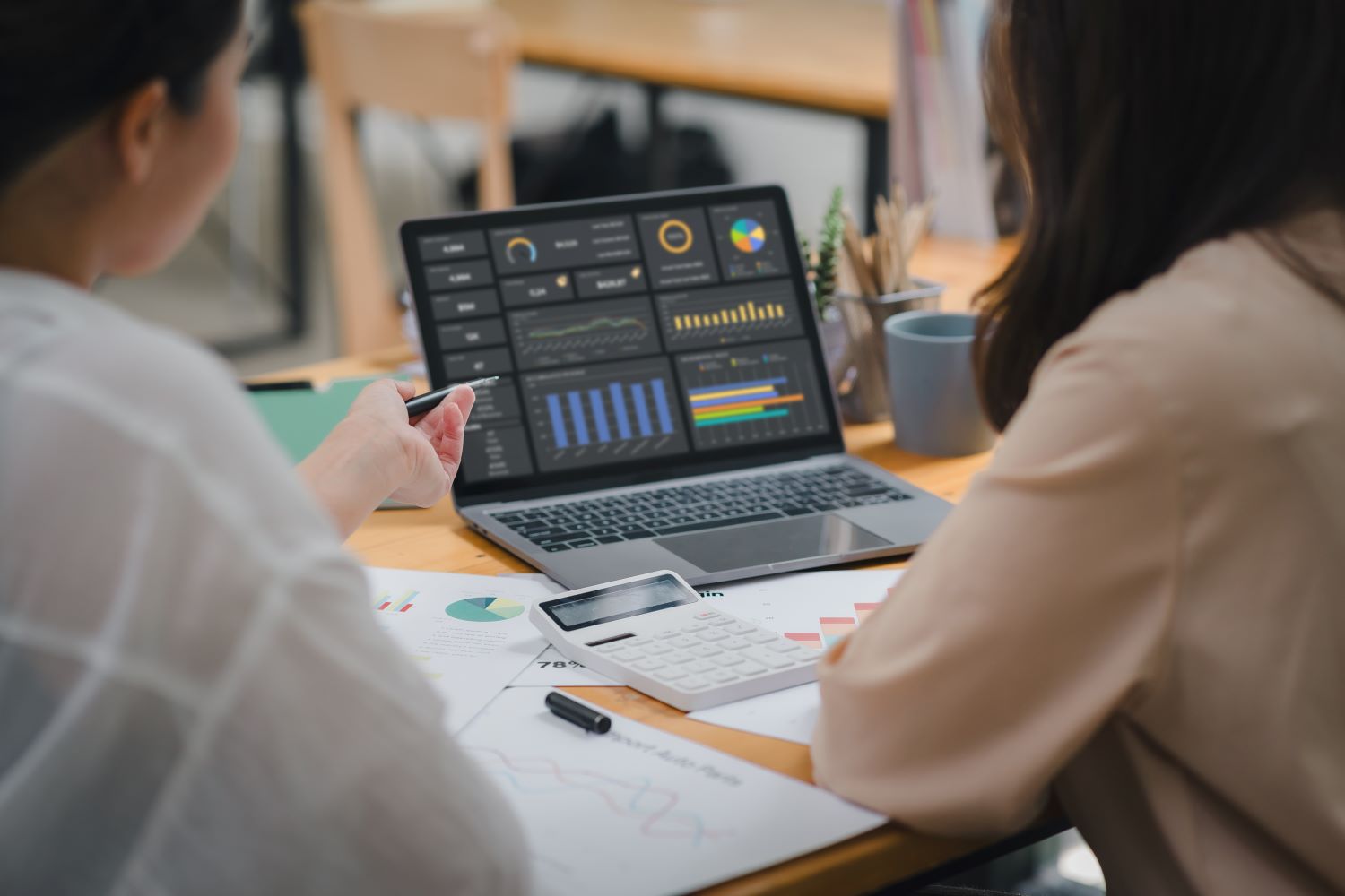Two women reviewing investment stats on laptop